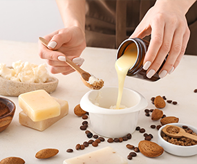 Pouring exotic butter into a bowl surrounded by natural ingredients for skincare hydration and nourishment